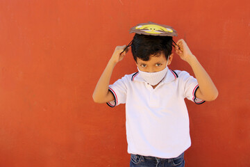 Latin little boy in uniform shirt proudly and happily shows the lion mask he made for school...