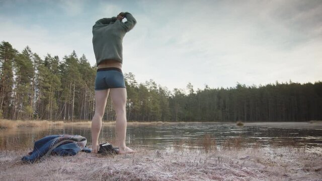 SLIDER - A fit, muscular athletic ice bather removes his top and prepares to enter