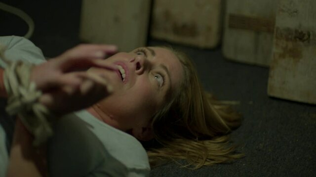 Scared and tied up woman being approached by kidnapper - close