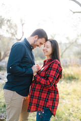 Smiling man holding hands of pregnant woman touching his forehead to her forehead