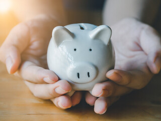 Portrait of teen boy holding and giving white piggy bank in garden. Concept for saving money, loan, property ladder, financial, real estate investment and bonus.