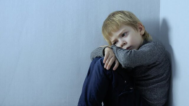 Domestic violence concept. sad upset boy sitting in corner. Child punished sitting crying in the corner lifestyle . Child abuse