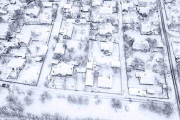 aerial view of suburban neighborhood with snow-covered houses on winter day.