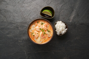 Tom Yam kung Spicy Thai soup with shrimp, seafood, coconut milk and chili pepper in bowl 