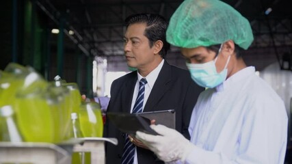food scientist worker team wearing face mask and asian manager checking quality control with  of juice bottle with tablet computer  in industrial water factory. inspection in line production beverage.
