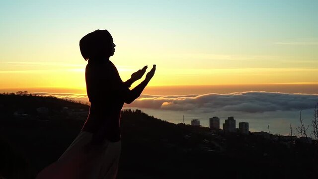 Muslim prayer. Silhouette of Muslim woman making Dua to Allah outdoor. Beautiful dawn, sunrise. Muslim refugees and displaced people
