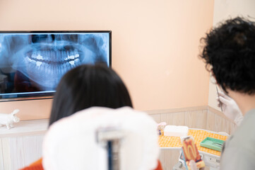 A doctor smiling and explaining to a patient in a dental office.