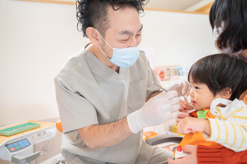頑張って幼児の治療をしようとする小児歯科医