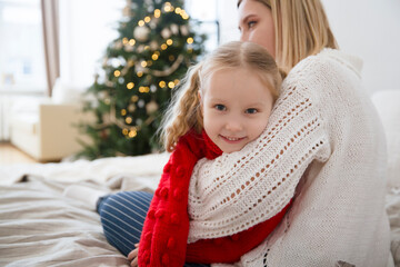 family on Christmas holidays together at home. mom and little daughter hug and play at home on Christmas Day