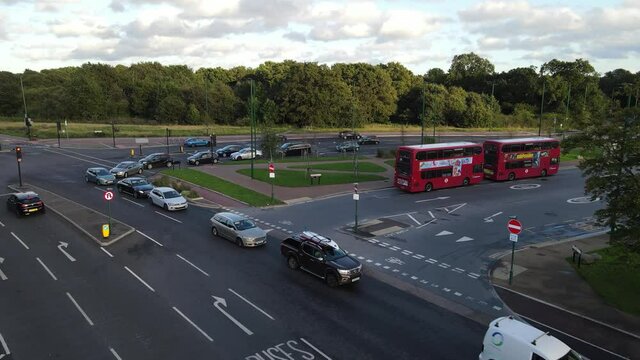 ars waiting at traffic lights at crossroad. Park or forest with trees in background. London, UK