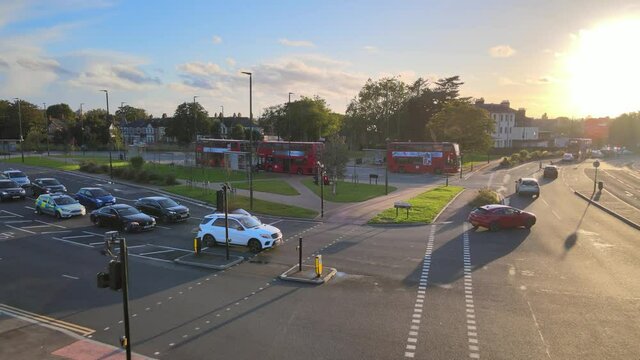 ars driving on multilane road in urban neighbourhood. Tall apartment building against setting sun. London, UK