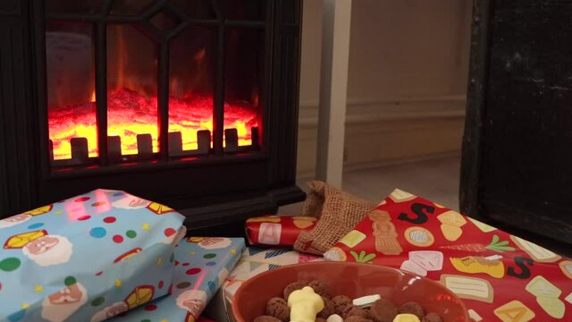 Bowl of Sinterklaas holiday candy and colorful wrapped gifts in front of a fireplace
