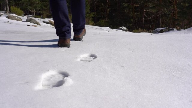 Man leaving footprints on the freshly fallen snow on the mountain in the foreground. Slow motion.