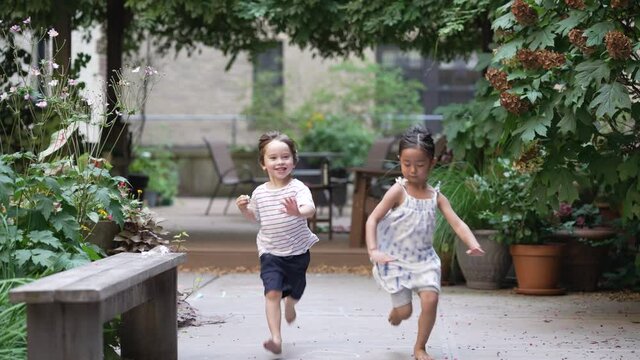 Multiracial kids running into the camera, girl and boy having fun in backyard