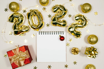 Golden 2022 balloons, gift, balls, notepad isolated on grey background. Helium balloons, gold foil numbers. Numbers for Happy New Year 2022.