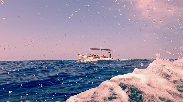 Low-angle water surface pov of boat wake trail with Riserva dello Zingaro natural reserve of Sicily in background. Italy