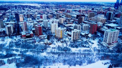 Aerial hold over Downtown Edmonton Victoria Park Edge on a winter day birds eye view over the high rises of apartments and condominiums with snow covered trees realty properties for rent or for sale