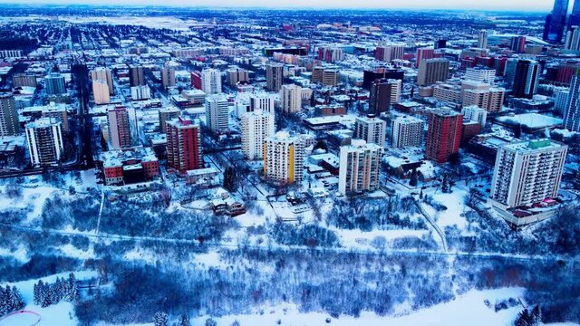 Aerial hold over Downtown Edmonton Victoria Park Edge on a winter day birds eye view over the high rises of apartments and condominiums with snow covered trees realty properties for rent or for sale