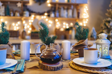 a teapot on the table in decorated kitchen for new year. electric garlands.