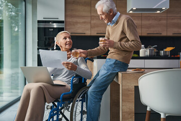 Naklejka premium Delighted mature man giving tea to his wife