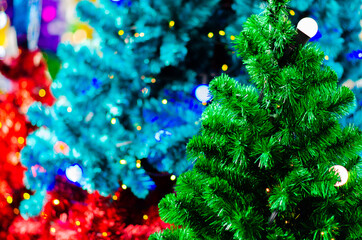 Fototapeta na wymiar Green Christmas tree with light bulb and blurred focus of colorful Christmas trees.