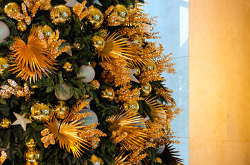 Golden and silver color baubles, ornaments and dry leaves decorated on big Christmas tree.