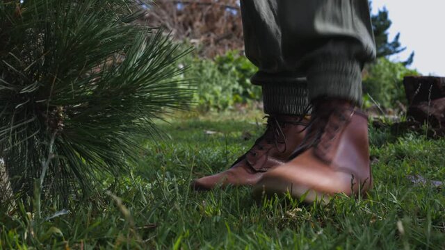 Female hand picks up axe with leather shoes and pine tree