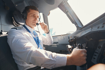 Pilot bringing microphone of headset to his mouth - obrazy, fototapety, plakaty