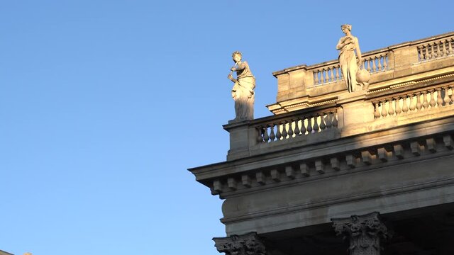 Female statues on the roof of the Bordeaux Opera house palace in France on a clear day with blue sky, Handheld telephoto shot