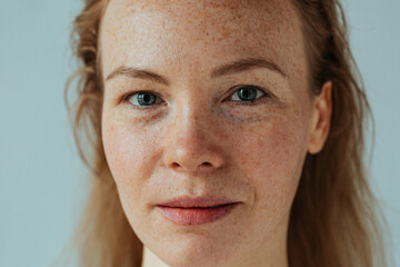 Beautiful woman with read hair and freckles. Close up portrait against black background