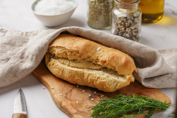 A loaf of homemade wheat bread on a wooden board on marble surface