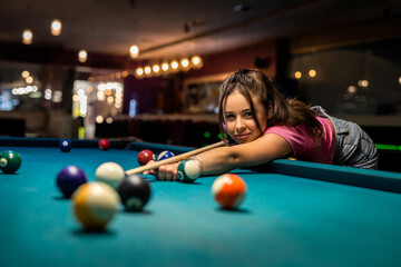 Happy caucasian woman wear casual cloth playing a game of billiards