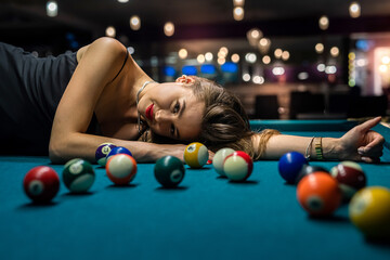 sexy girl lies on the snooker table among the balls