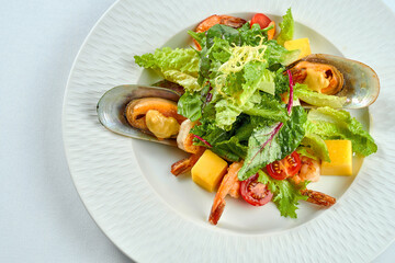 Shrimp and mussel salad, mango in a white plate on a tablecloth