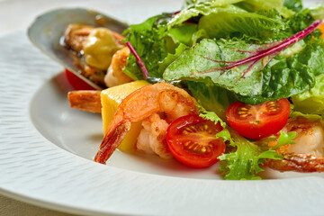 Shrimp and mussel salad, mango in a white plate on a tablecloth