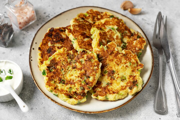 Homemade potato pancakes with cottage cheese and green onions in a ceramic plate on a bright kitchen table close-up. A traditional dish of European cuisine made of vegetables