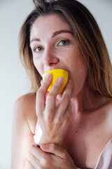 beautiful blonde woman eating yellow sour lemon