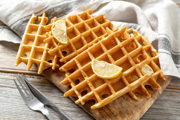 Ginger lemon waffles with honey on a serving board on a light gray wooden culinary background. Delicious healthy homemade cakes that increase immunity on the kitchen table close-up