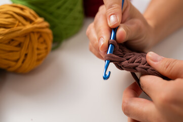 Close-up of a woman crocheting a basket of cotton yarn.
