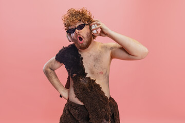 Cropped portrait of man in character of neanderthal wearing stylish sunglasses and listening to...