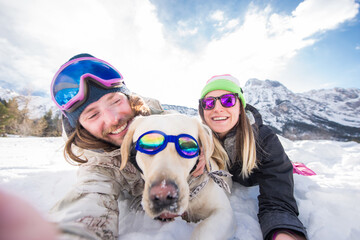 Couple playing with dog in the snow