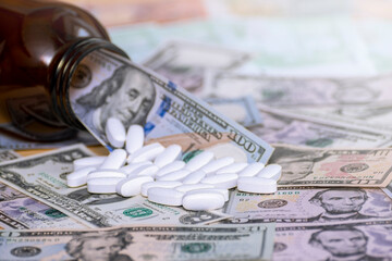 The tablets are scattered from the glass packaging on the banknotes. The concept is to raise the price of medicines. Investing in pharmaceuticals.