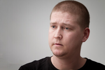 Fototapeta premium A young slavic man with short hair looking concerned on a plain background. 