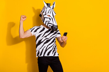 Photo of excited freak guy blogger in zebra mask use smart phone fist up win followers post...