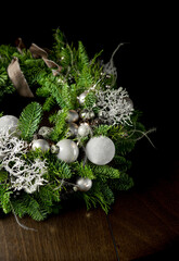 Christmas wreath made of natural branches (nobilis fir and dried plants) and Christmas balls on a wooden table background