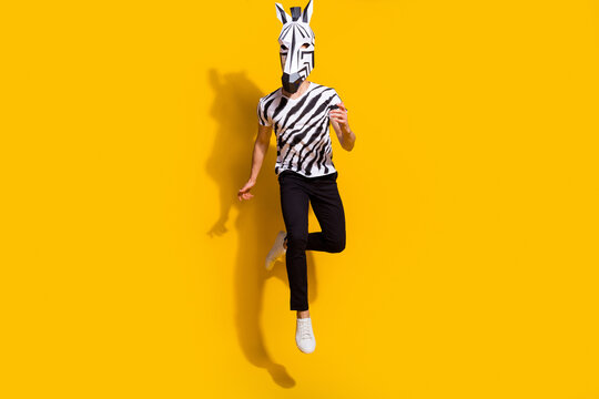 Full size photo of freak surreal guy in zebra horse mask jump up isolated over bright yellow color background