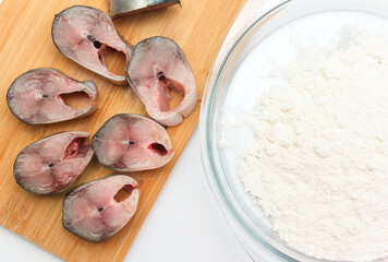 cooking mackerel, pieces of raw fish and flour