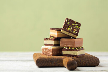 Different cremino - italian chocolate,  originally from Piedmont, composed by different layers, made with gianduja chocolate, coffee, pistacchio and hazelnut paste. Pistacchio color background.