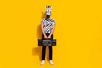 Full length photo of freak crazy unusual guy in zebra costume hold boom box isolated over yellow...