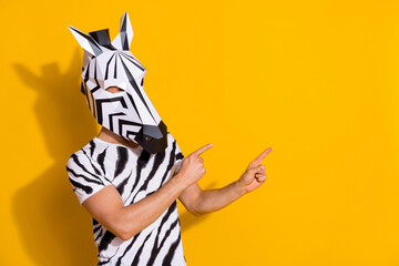 Photo of unusual guy in zebra mask point finger empty space demonstrate theme event promo isolated over yellow color background - obrazy, fototapety, plakaty